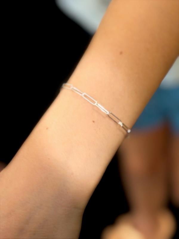 A silver paperclip-link permanent bracelet worn on a wrist.